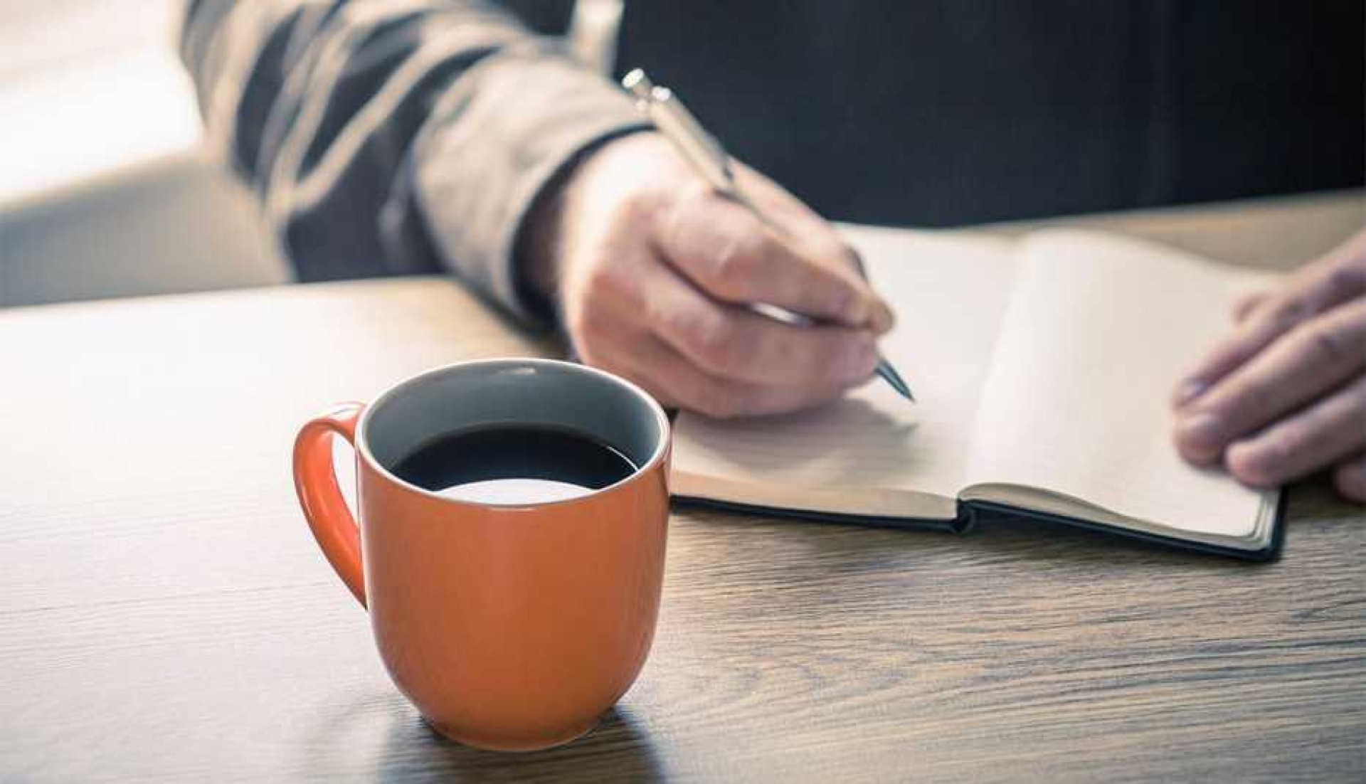 persona escribiendo journaling de gratitud en casa con taza de café