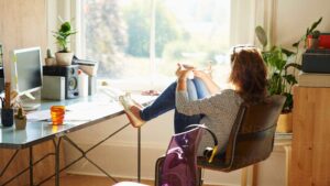 mujer trabajando en escritorio de pie en casa junto a ventana luminosa